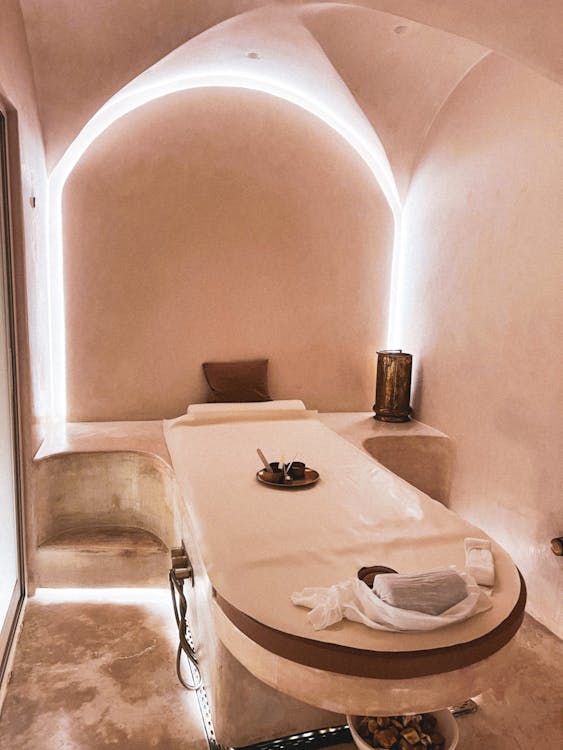 Minimalist treatment room at a Dubai massage spa with warm ambient lighting and a single draped bed in soft focus